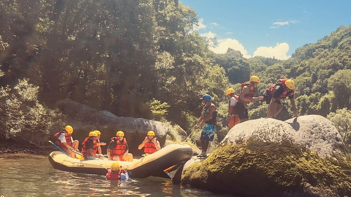 Guests climbing a moss-covered boulder in a Gunma gorge