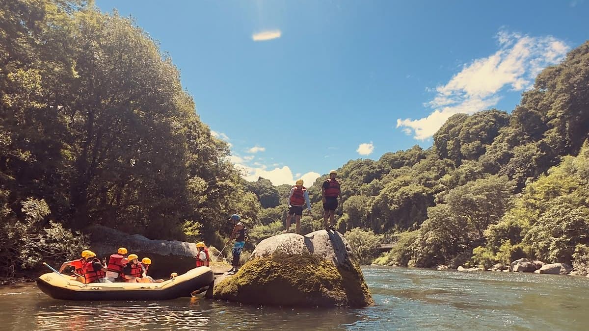 Sunlit gorge on the Tone River with a raft beside a large boulder