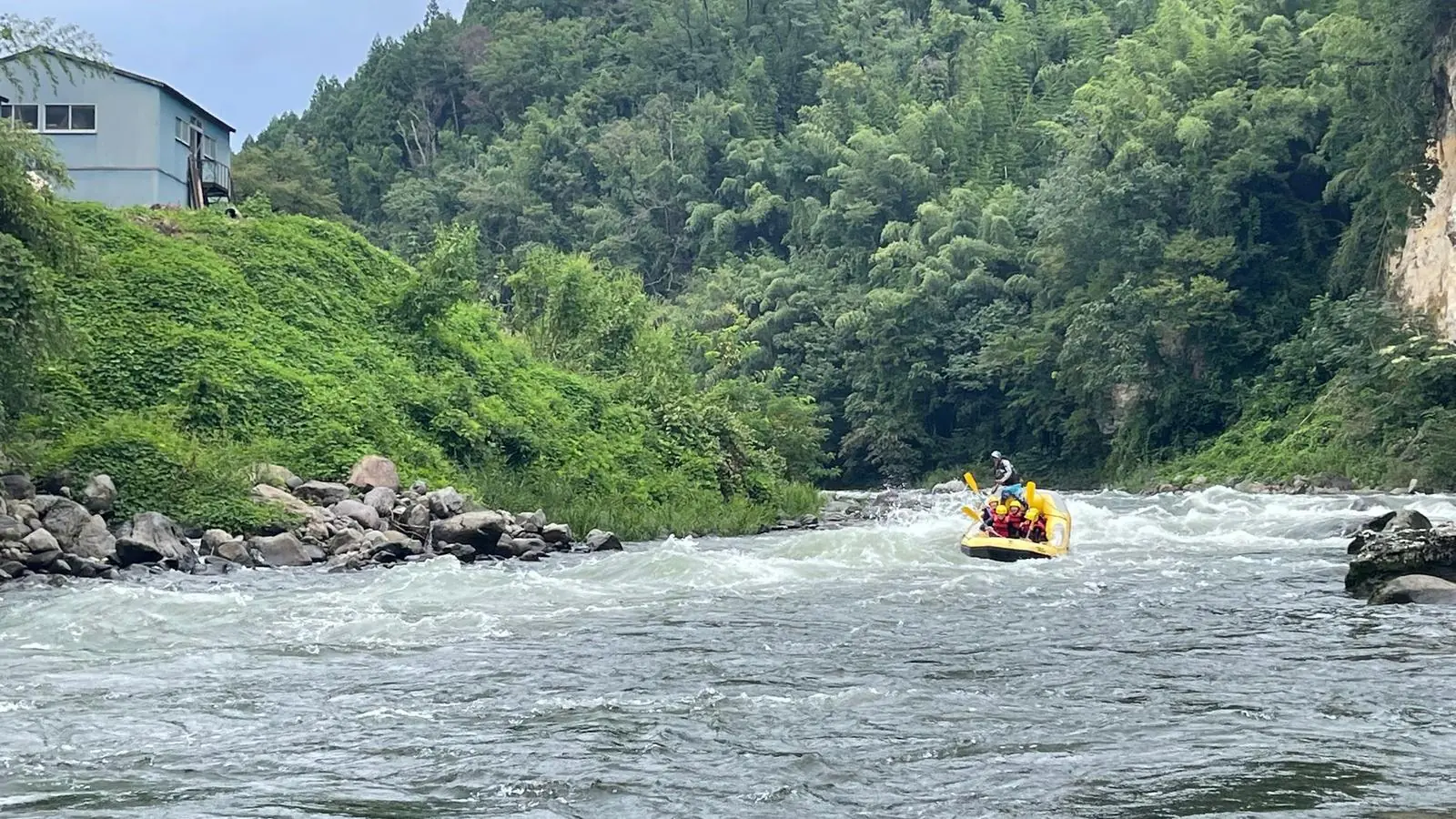 The Tone River flowing through a forested gorge in Gunma, with a raft in the distance